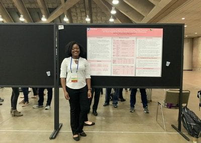 A Member of the Lab stands next to her research at the conference